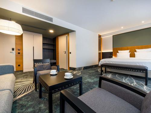 a hotel room with a bed and a living room at Mercure Palanga Vanagupe Resort & SPA in Palanga