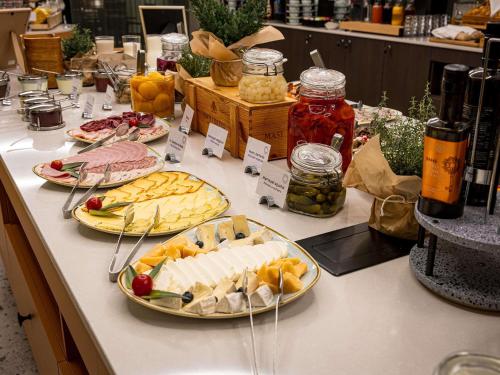 a buffet with plates of food on a table at Mercure Palanga Vanagupe Resort & SPA in Palanga
