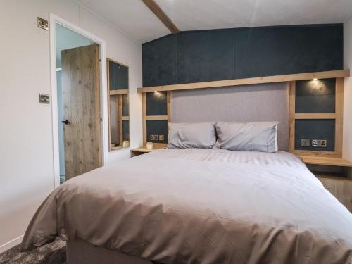 a bedroom with a large bed and a blue wall at Meadows Park 3 in Hull
