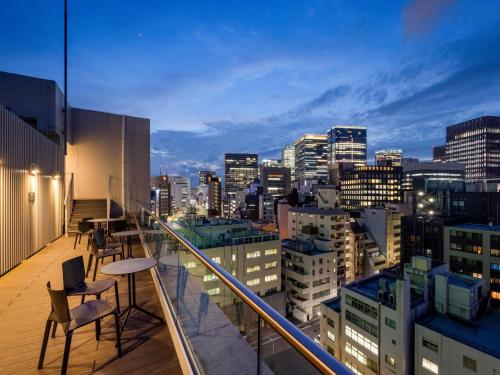 Un balcón con sillas y vista a una ciudad. en ibis Styles Tokyo Ginza East, en Tokio