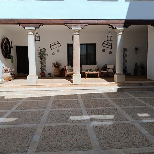 a courtyard with a building with pillars and chairs at La Fragua de Domingo in Villanueva de los Infantes
