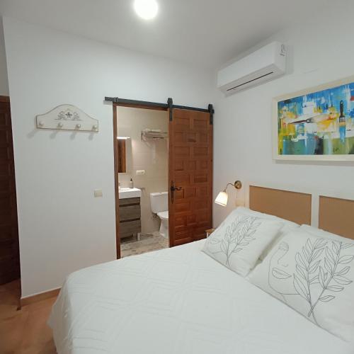a bedroom with a white bed and a bathroom at La Fragua de Domingo in Villanueva de los Infantes