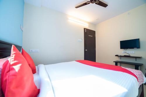 - une chambre avec un lit doté d'oreillers rouges et une télévision dans l'établissement Hotel Blue House, à Hyderabad