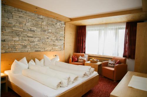 una habitación de hotel con una cama grande y sillas en Hotel Sportpension Carinthia, en Sölden