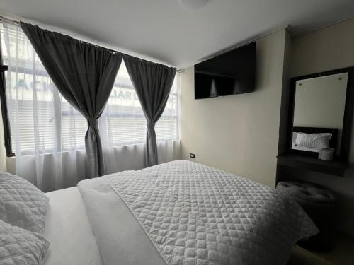 a bedroom with a white bed and a window at Hotel Monaco in Ipiales