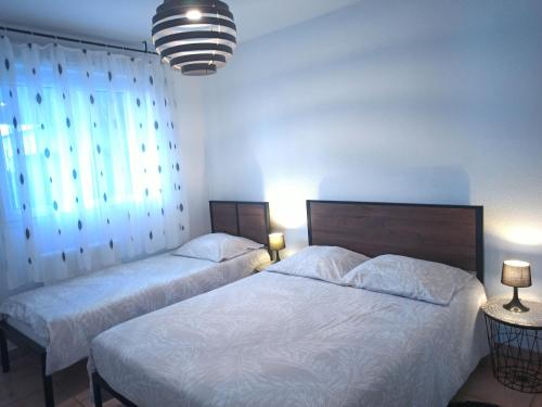 a bedroom with two beds and two lamps and a window at Appartement face à la Gare in Annemasse