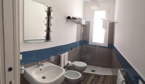 un bagno con lavandino, water e specchio di Le Cale Camera Privata in Residence a Favignana