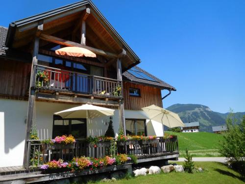 a house with a balcony with flowers and umbrellas at Appartements gosaukamm.com in Gosau