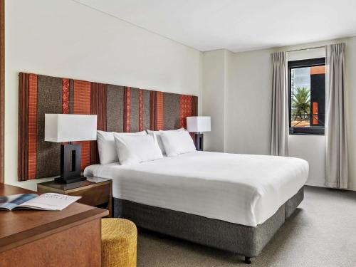 a hotel room with a large bed and a desk at Mantra on Hay Perth in Perth