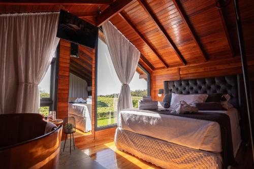 a bedroom with a bed and a large window at Capanna del Vale - Refúgio & Degustação no Vale dos Vinhedos in Bento Gonçalves