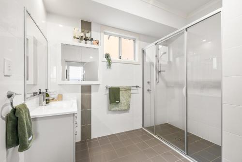 a white bathroom with a shower and a sink at Rocky Shores Hideaway in South West Rocks