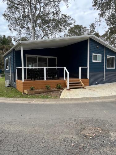 a blue manufactured home with a porch and a deck at Tasman Holiday Parks - Kioloa Beach in Kioloa