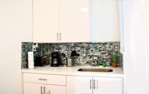 a kitchen with white cabinets and a sink at The Madison by the Gold Nests in Hollywood