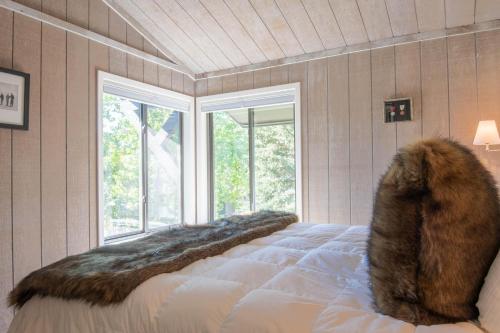 a bedroom with a bed with a fur blanket and windows at Villager Condo 1240 in Sun Valley