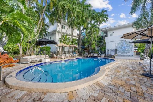 a swimming pool with palm trees in front of a building at Isle of Venice Residence and Marina in Fort Lauderdale