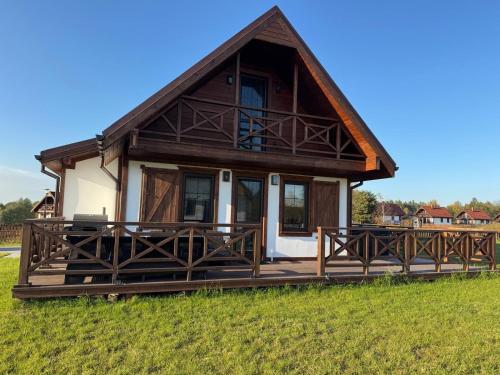 a house with a large deck in a field at Warmia Domek Bukowy in Woryty