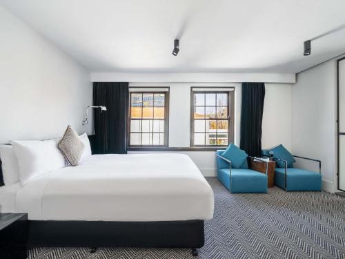 a hotel room with a bed and two blue chairs at Peppers Gallery Hotel in Canberra