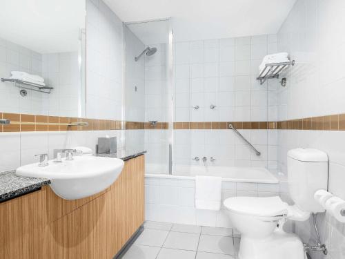 a bathroom with a sink and a toilet and a tub at Mantra on Russell in Melbourne