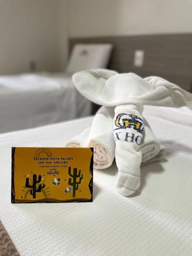 ein Handtuchtier, das mit einem Buch auf einem Bett liegt in der Unterkunft Max Hotel in Arcoverde