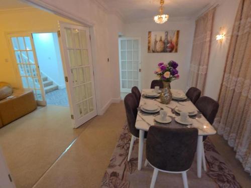 a dining room with a table with chairs and flowers on it at First Class Luxurious Apartment London Finchley in Brent Station