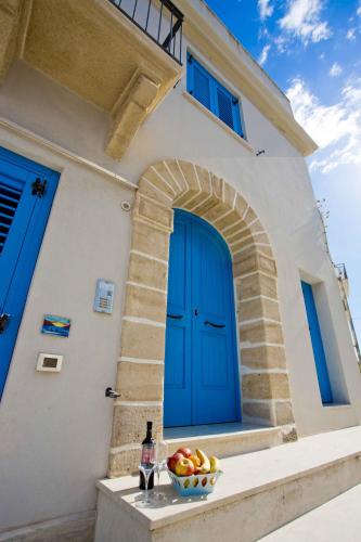 a house with a blue door and a bowl of fruit at Terra del Sole in Favignana