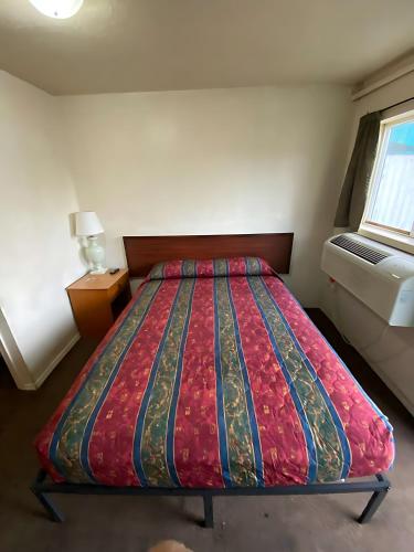 a bedroom with a bed with a red comforter and a window at Tacoma Center Motel in Tacoma