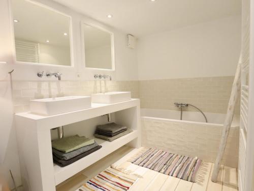 a white bathroom with two sinks and a tub at Agathe in Laforêt