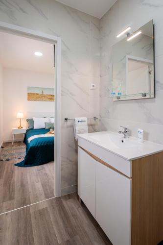 a white bathroom with a sink and a bed at DesKanzo Guest House - Silva Brinco in São Mamede de Infesta