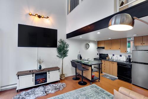a kitchen with a table and a tv on the wall at Stylish Two-Story Loft with Rooftop Deck in Vancouver