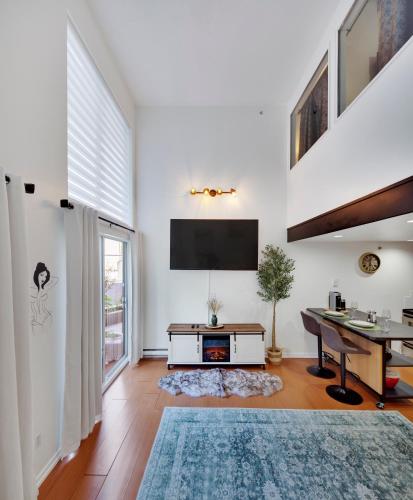 a living room with a desk and a tv on the wall at Stylish Two-Story Loft with Rooftop Deck in Vancouver