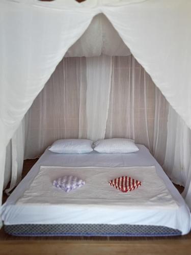 a bed in a tent with two pillows on it at Parfray Homestay Raja Ampat in Airborei