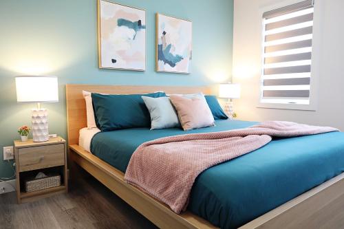 a bedroom with a bed with blue sheets and pillows at Chappelle with AC King Beds Fenced Yard Garage in Edmonton