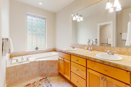 ein Badezimmer mit 2 Waschbecken, einer Badewanne und einem Spiegel in der Unterkunft Eagle Crest Village Lp Getaway in Redmond