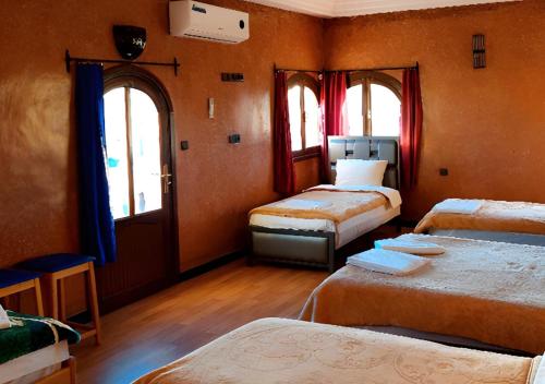 een kamer met 3 bedden en 2 ramen bij SUD-EST palace in Aït Igad