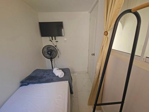 a small room with a bed and a fan at Casa de Huéspedes Colibrí in Envigado