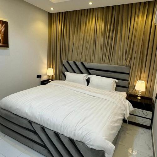 a bedroom with a large white bed with two lamps at Kingstone in Amman