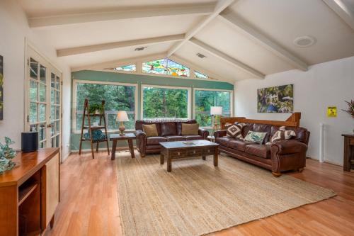 a living room with leather furniture and a large window at Sierra Mountain Escape - Brand new spa/game room! in Yosemite Forks