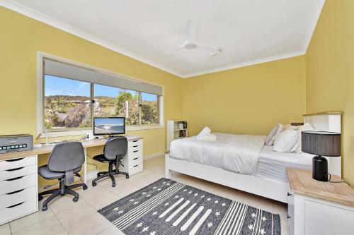 Un dormitorio con una cama y un escritorio con una computadora. en Salt and Paws at Fingal Bay, en Fingal Bay
