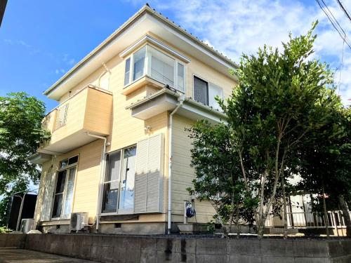 a yellow house with a tree in front of it at ペットと泊まれる一棟貸し 海の駅九十九里まで徒歩15分 はうす41マイルズ in Katakai