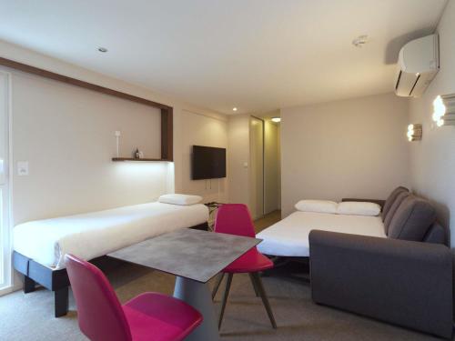 a hotel room with two beds and a couch at Greet Hôtel Dijon Sud Longvic in Longvic
