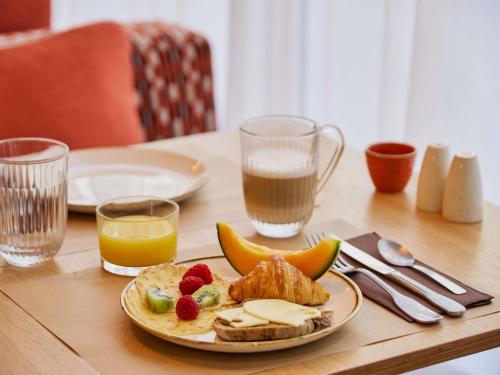 Una mesa con un plato de comida y un vaso de leche. en Mercure Saint Raphael Centre Plage, en Saint-Raphaël