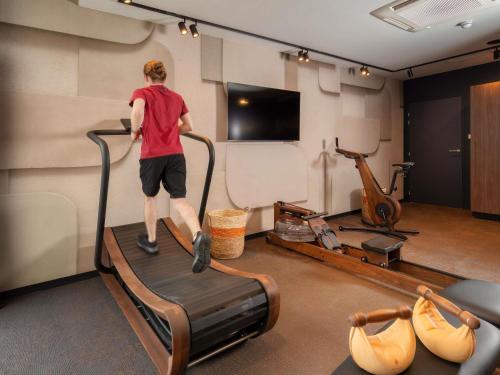 a man is standing on a treadmill in a gym at Novotel Rouen Centre Cathédrale in Rouen
