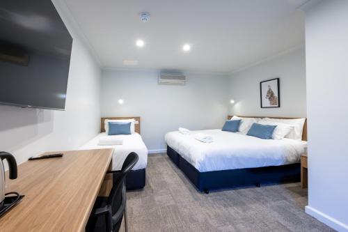 a hotel room with two beds and a desk at Claremont Hotel in Claremont
