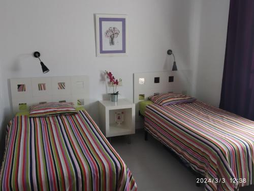 a bedroom with two beds and a table with flowers at Paraíso Veracoast in Vera