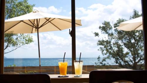 two glasses of orange juice sitting on a table with an umbrella at Yuinoya MITSUBACHI in Imabari