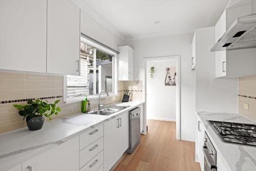 a white kitchen with white cabinets and a window at Modern Single Room in Botany - Mins to Airport - Shared Bathroom in Sydney