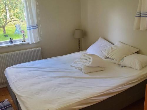a bed with white sheets and pillows and a window at Cozy Getaway near Forest and Lake in Insjön