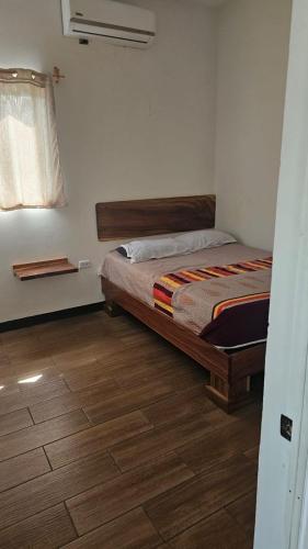een slaapkamer met een bed en een houten vloer bij Villas Campos Monterrico in El Banco
