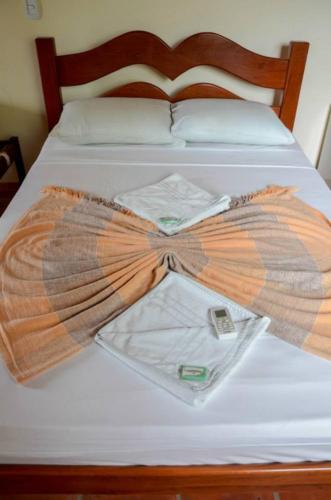 a bed with a dress and a shirt on it at Pousada Sitio Phoenix in Prea