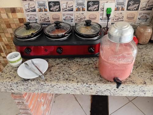 a counter with a stove with two pots of food at Pousada Pelourinho in Mucuri